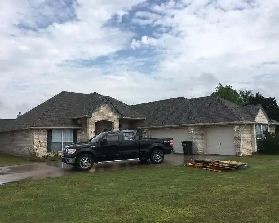 House with new dark shingle roof, pickup truck and debris in yard, C&A Roofing & Construction