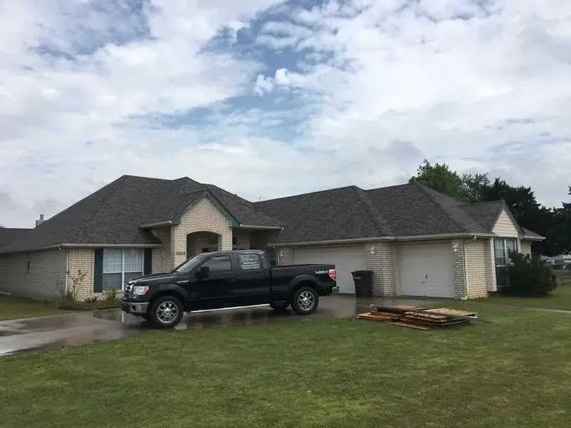House with new dark shingle roof, pickup truck and debris in yard, C&A Roofing & Construction