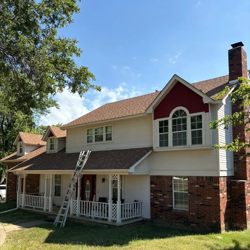 Two-story house roof work in progress, ladder at porch, C&A Roofing & Construction