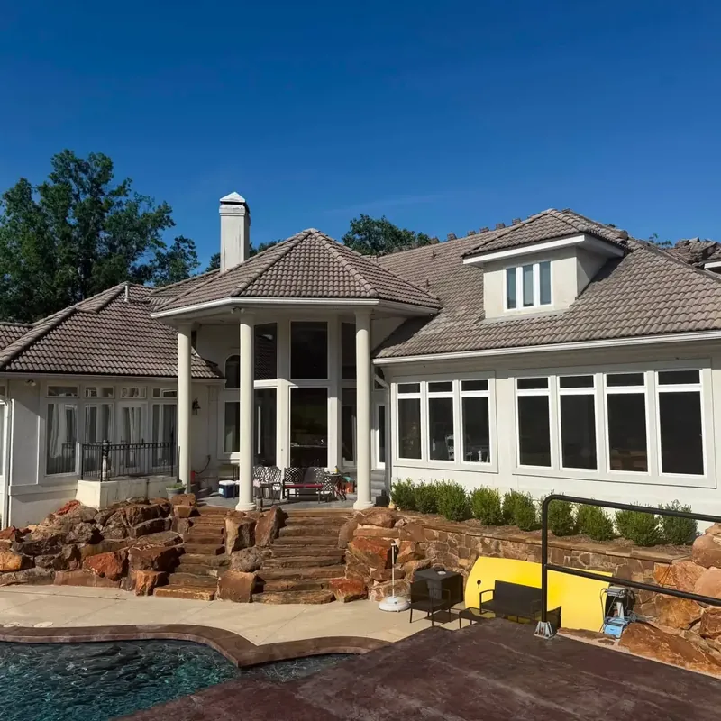Stucco custom home with tile roof above stone patio and pool, C&A Roofing & Construction