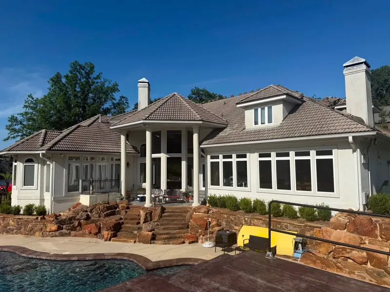 Stucco custom home with tile roof above stone patio and pool, C&A Roofing & Construction