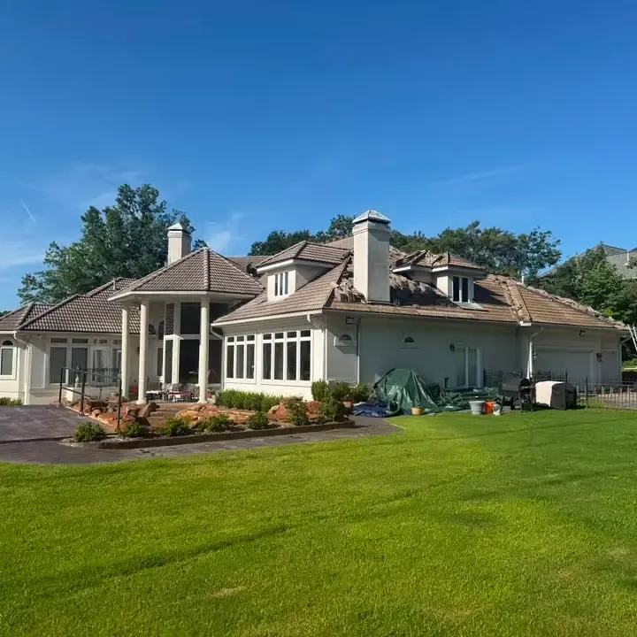 Stucco home with tile roof seen across lawn, C&A Roofing & Construction