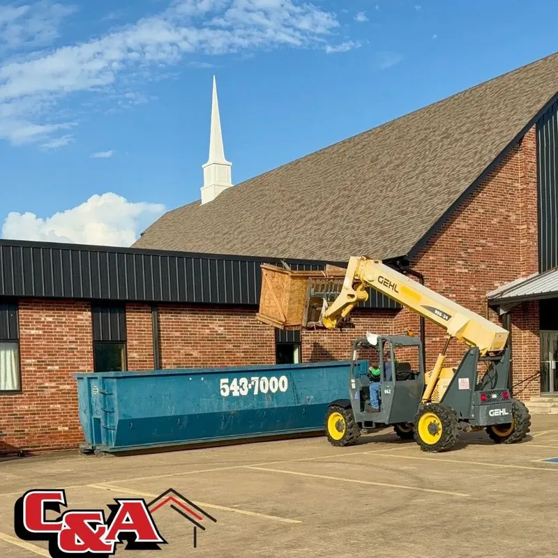 Telehandler loading debris into dumpster at church, C&A Roofing & Construction