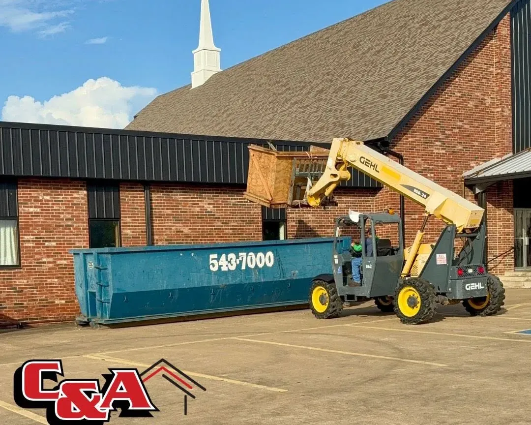 Telehandler loading debris into dumpster at church, C&A Roofing & Construction