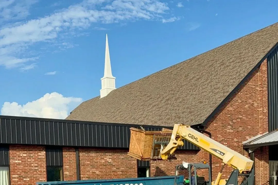 Telehandler loading debris into dumpster at church, C&A Roofing & Construction