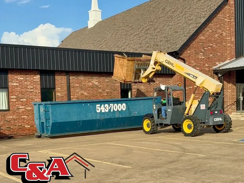 Telehandler loading debris into dumpster at church, C&A Roofing & Construction