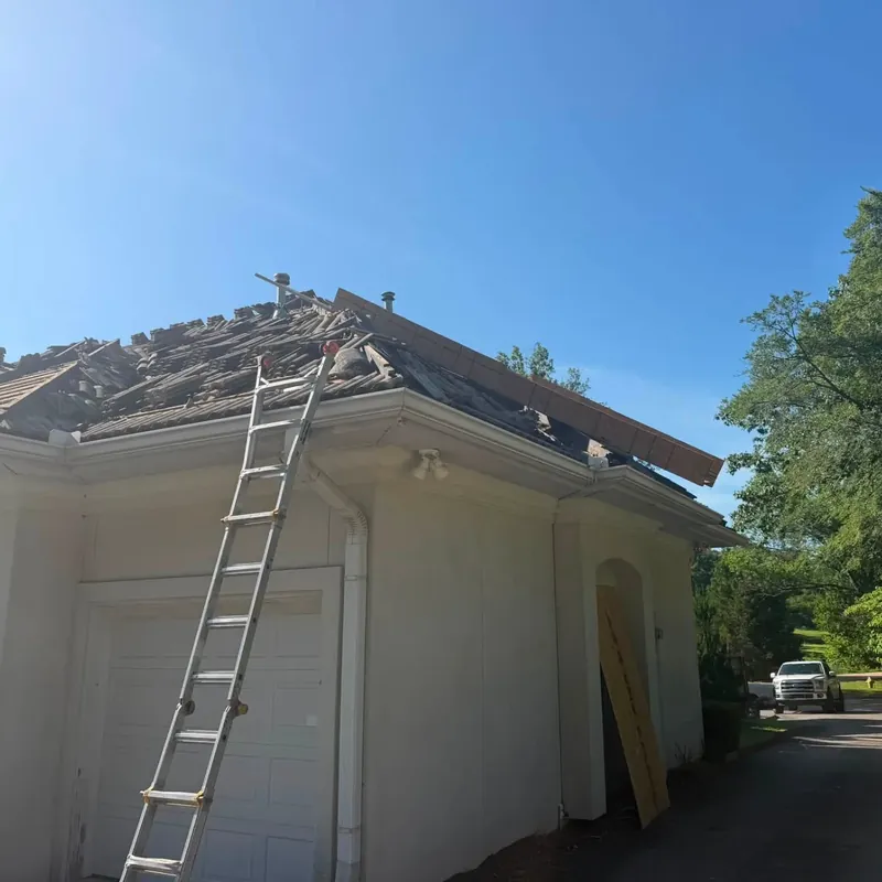 Tile roof partly removed, ladder against stucco house, C&A Roofing & Construction
