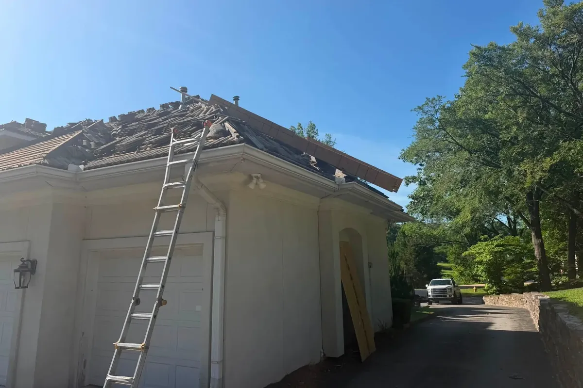 Tile roof partly removed, ladder against stucco house, C&A Roofing & Construction