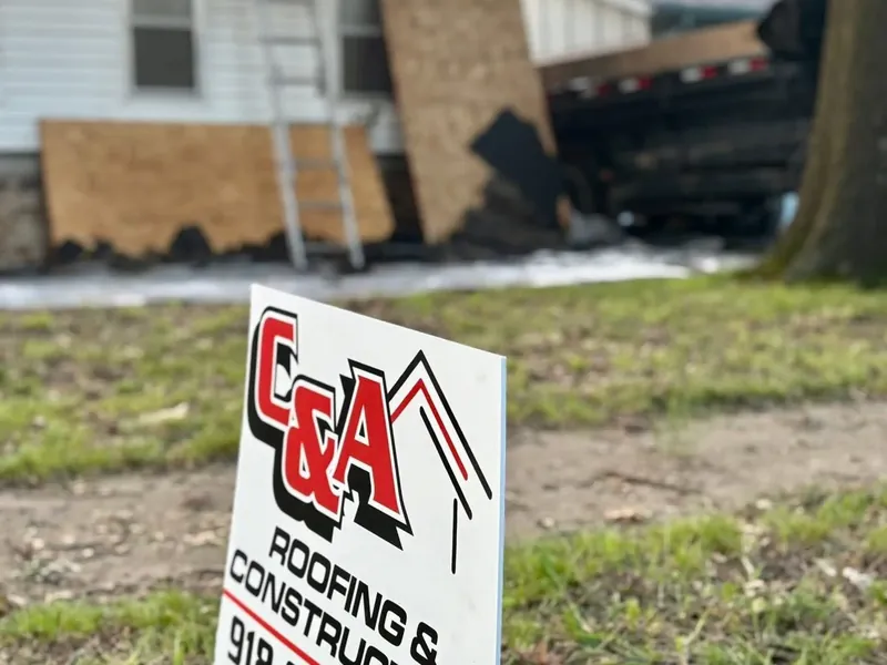 C&A yard sign in front of house with boarded damage, C&A Roofing & Construction