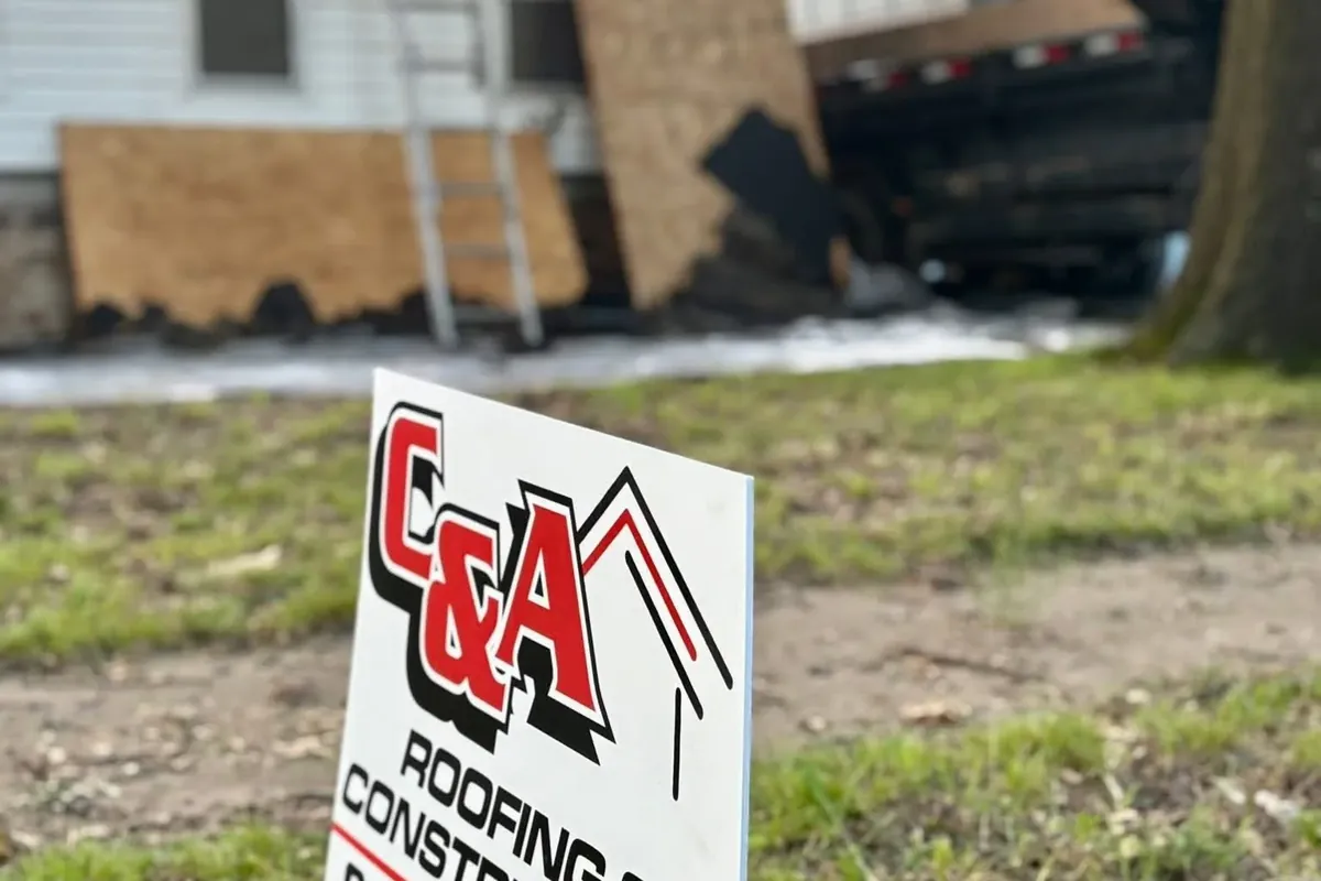 C&A yard sign in front of house with boarded damage, C&A Roofing & Construction