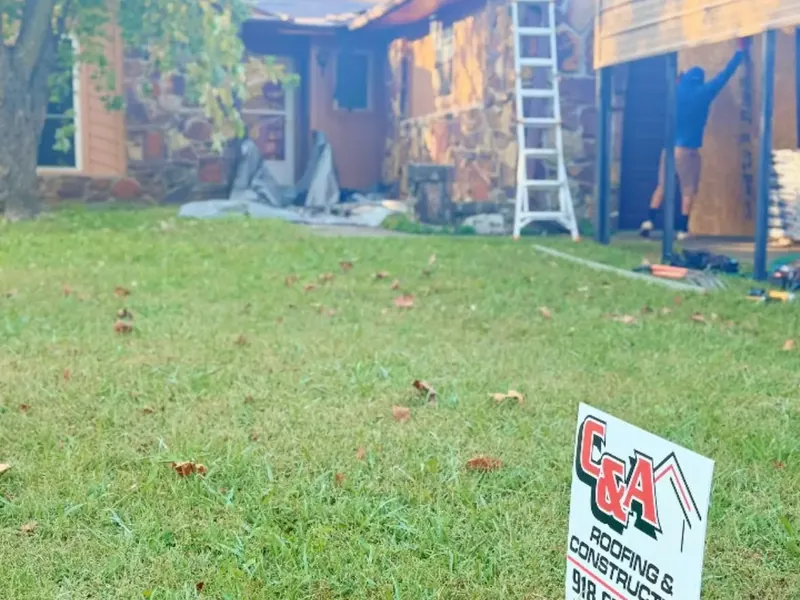 Crew on ladder working on house exterior and carport, yard sign, C&A Roofing & Construction