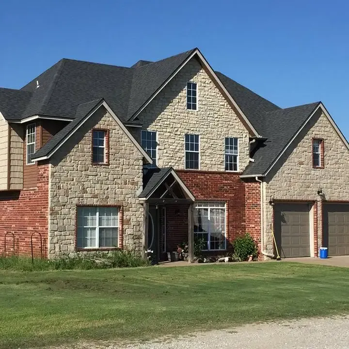 Two-story stone and brick house with new dark shingle roof, C&A Roofing & Construction