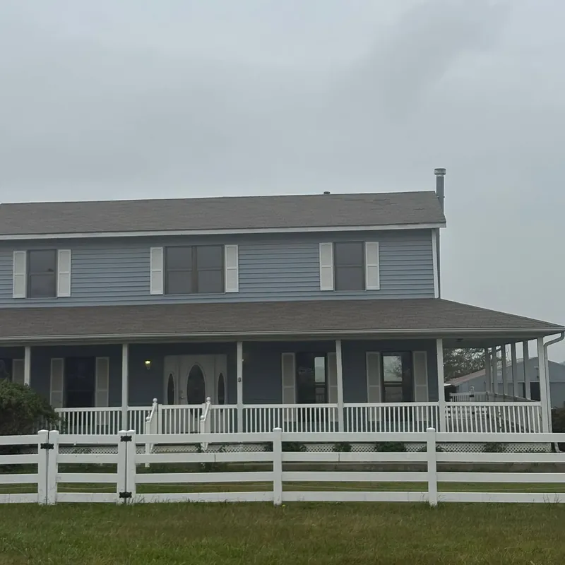 Two-story house gray shingles, blue siding, wraparound porch, C&A Roofing & Construction