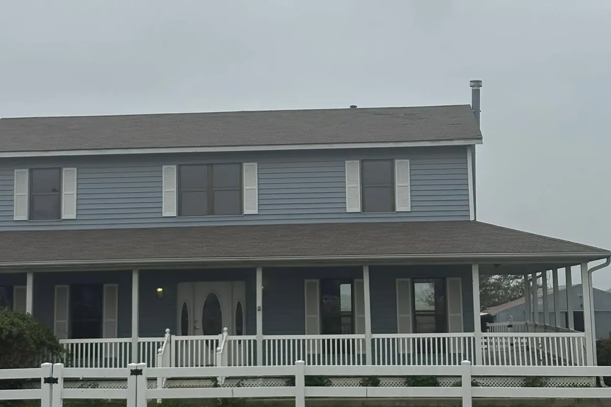 Two-story house gray shingles, blue siding, wraparound porch, C&A Roofing & Construction