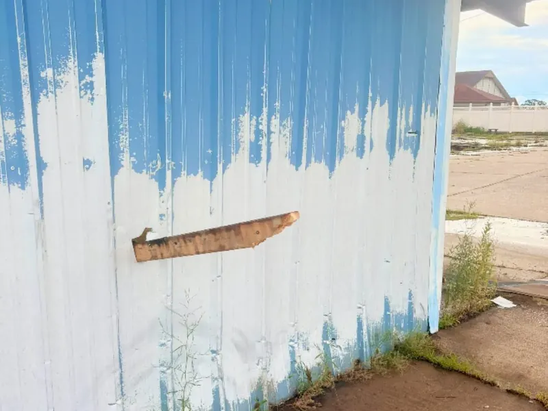 Peeling blue paint on white metal building wall, C&A Roofing & Construction