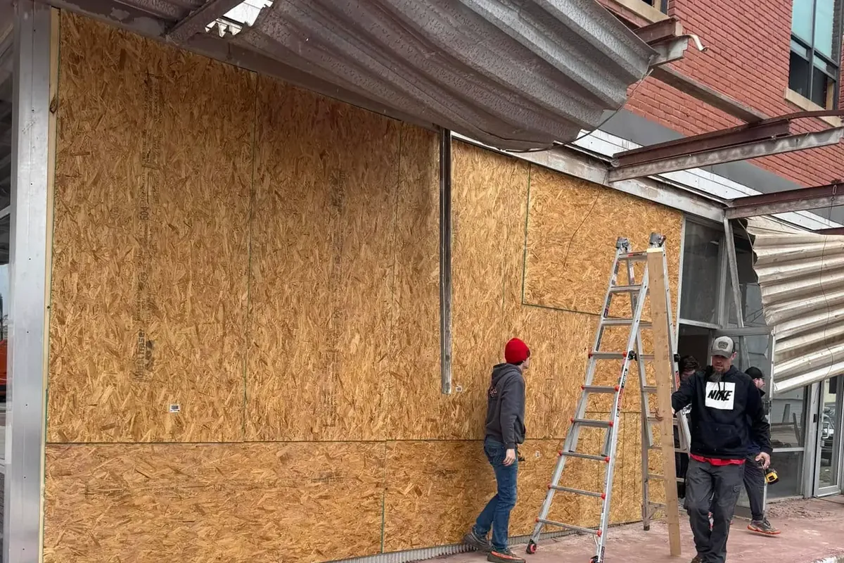 Crew boarding up storm-damaged commercial storefront with plywood, C&A Roofing & Construction