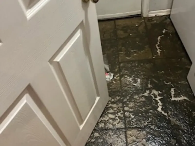 Dirty floodwater on laundry room floor by door, C&A Roofing & Construction